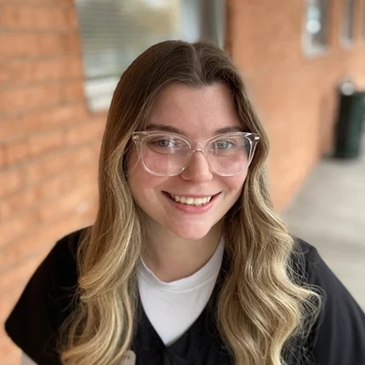 Georgia smiling in front of a brick wall.